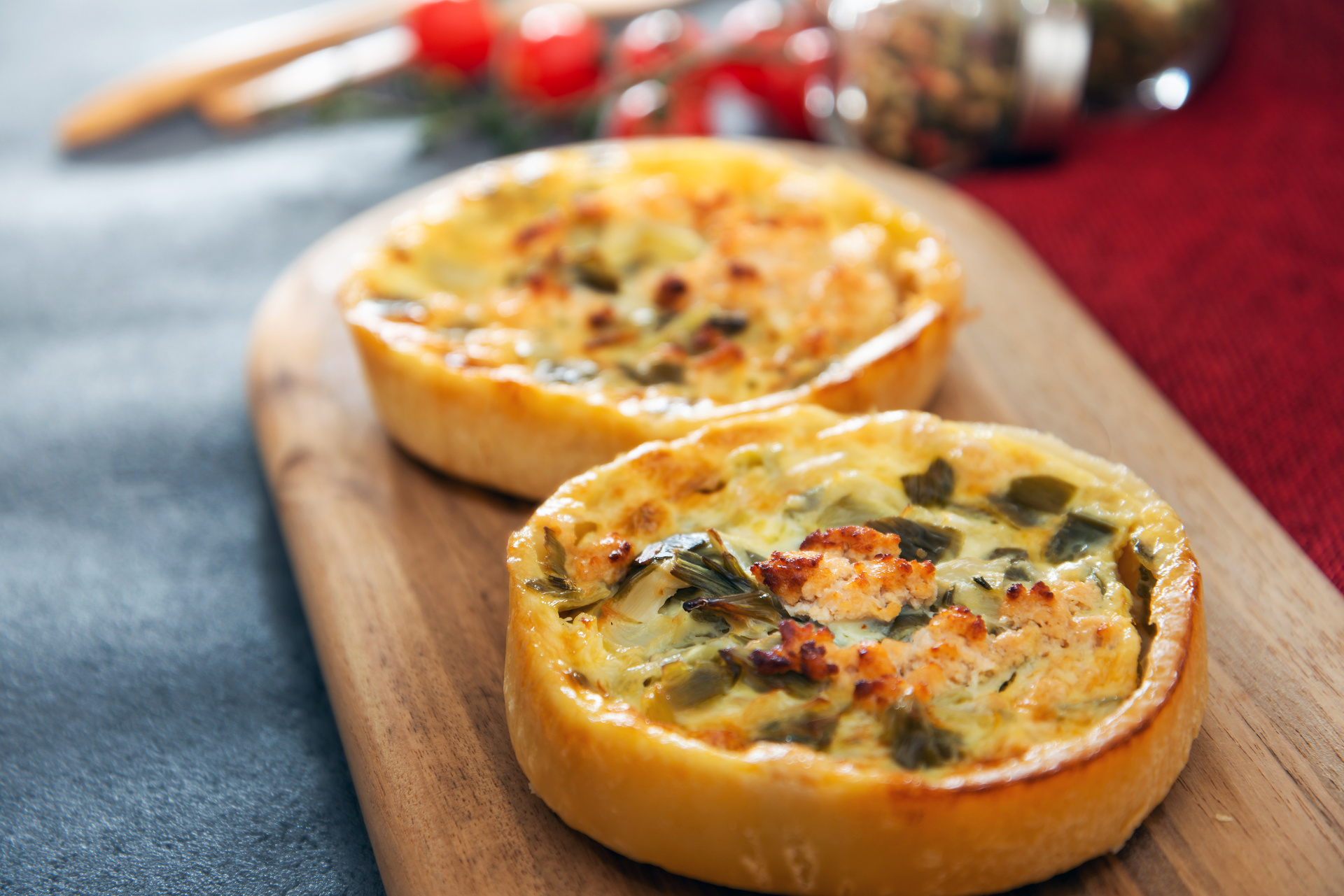 Fresh bakery quiches with savory fillings on a wooden serving board